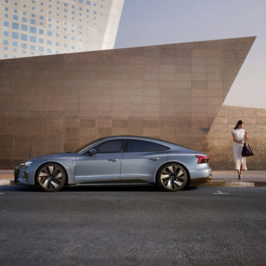 Sedan car parked on a city street with architectural structures in the background.