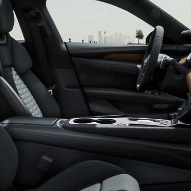Car interior with leather seats, center console, and view of a city skyline through the windshield.