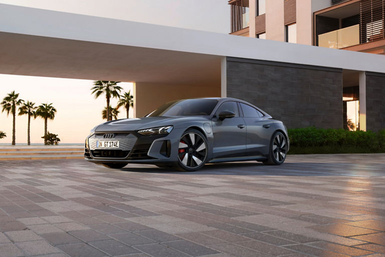 A grey sedan parked outside near palm trees at sunset.