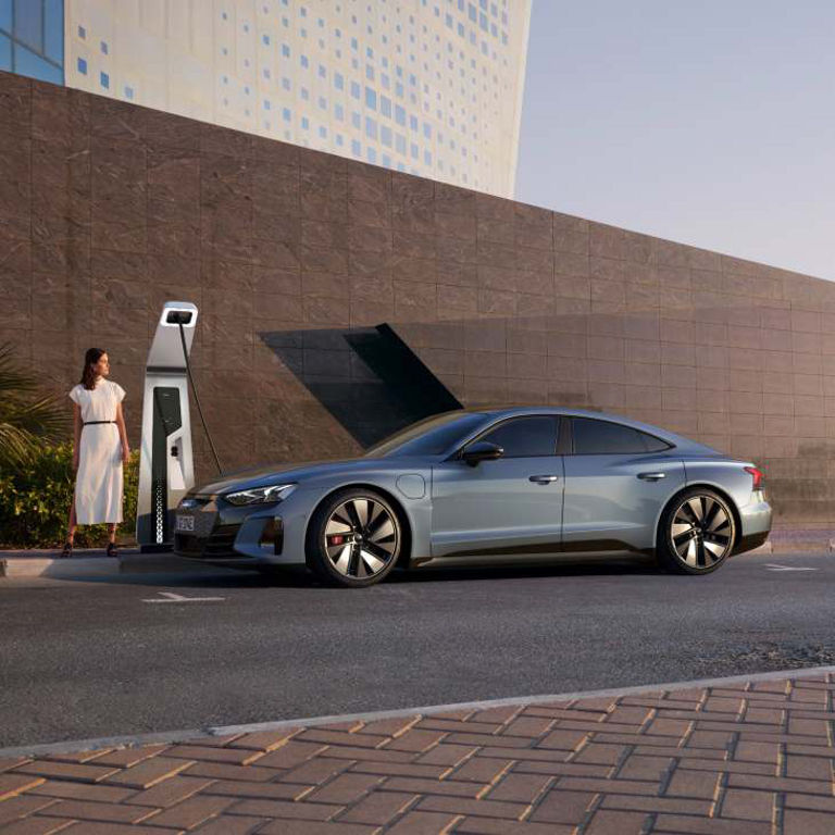 An electric car charging at a public charging station near a building.