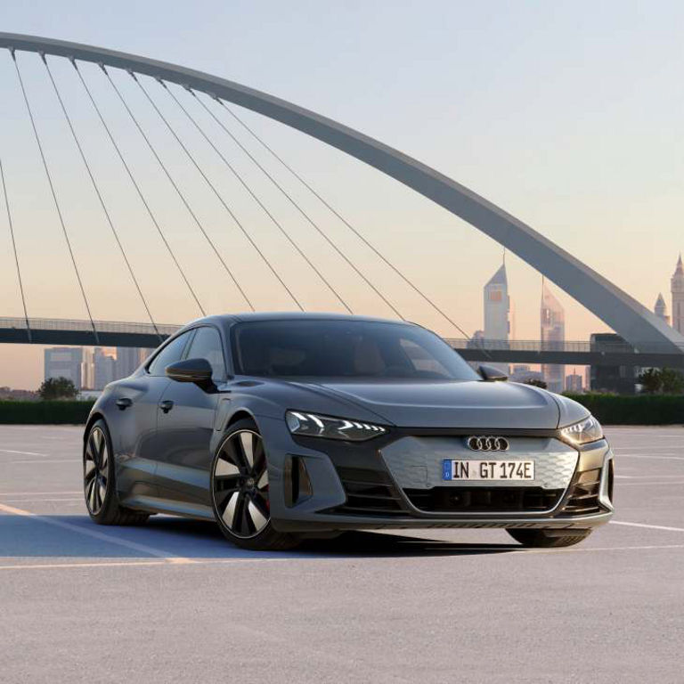 A grey Audi e-tron GT car on a bridge and skyline in the background.