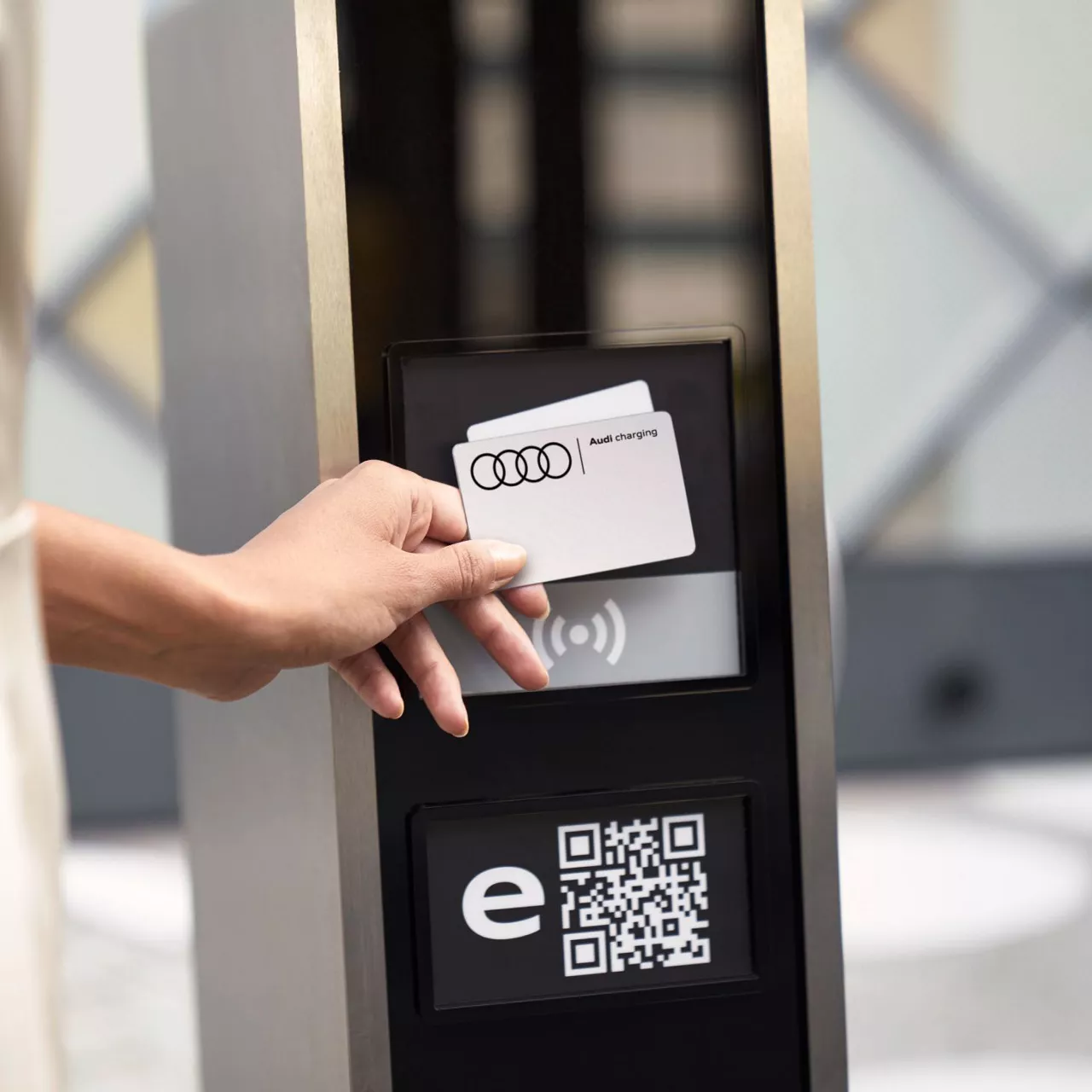 A hand holding up an Audi Charging card to a charging terminal