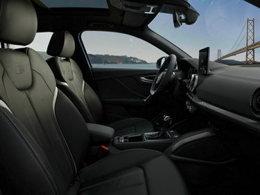 Interior view of a modern car with leather seats, center console, and view of a bridge through the window.