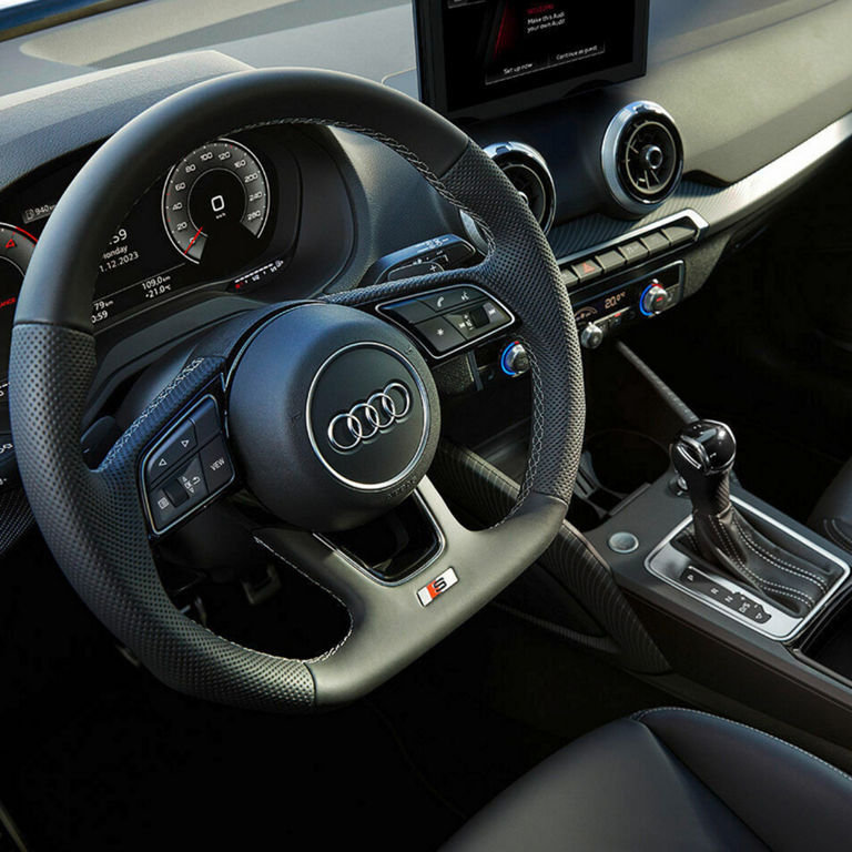 Interior of a car showing steering wheel, dashboard, gear shift, and multimedia system.