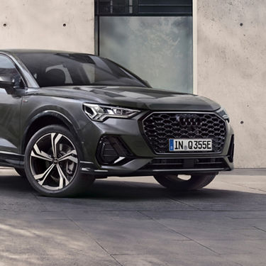 Side view of dark grey Audi Q3 outside modern building.