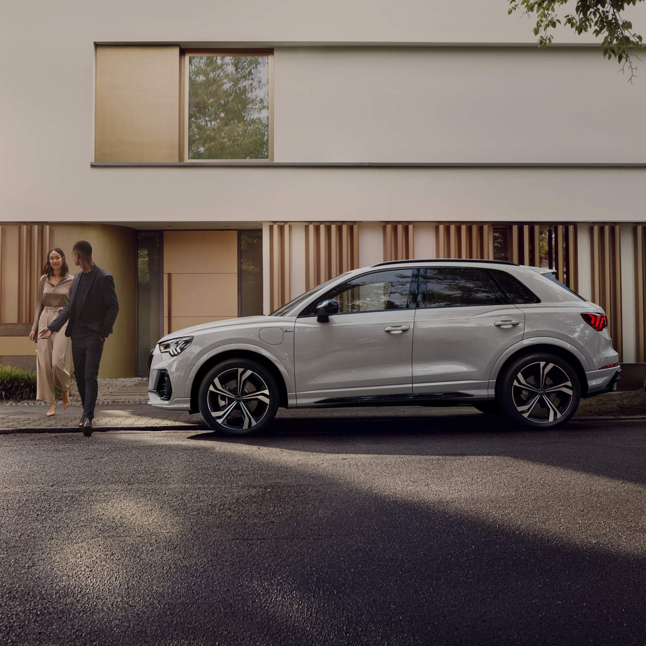 Man standing infront of Audi Q3 on side street.