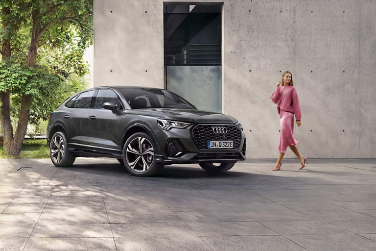Lady in pink outfit approaching Audi Q3 Sportback TFSI e outside house.