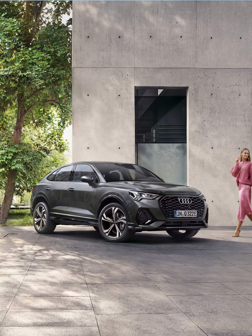 Lady in pink outfit approaching Audi Q3 Sportback TFSI e outside house.