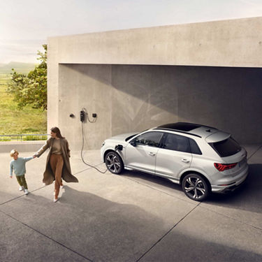  Woman holding child's hand walking away from charging Audi Q3 tfsi e.