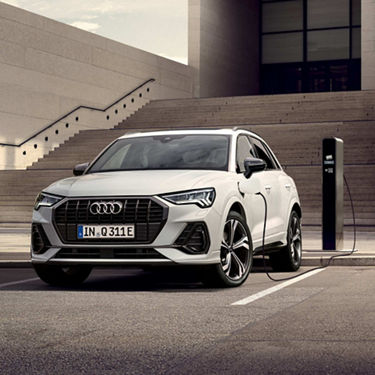 White Q3 Audi tfsi e charging in a parking bay. with step in the background.