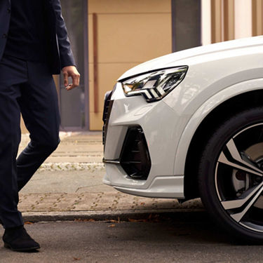 Close up side view of Audi Q3 tfsi e with a man approaching.
