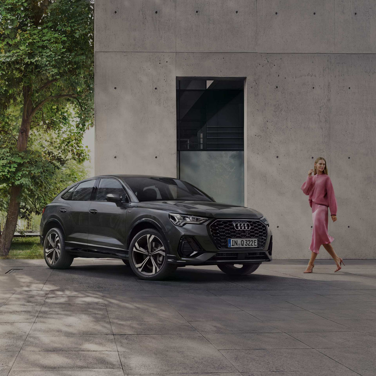 Lady in pink outfit looking over her shoulder walking towards Audi Q3.