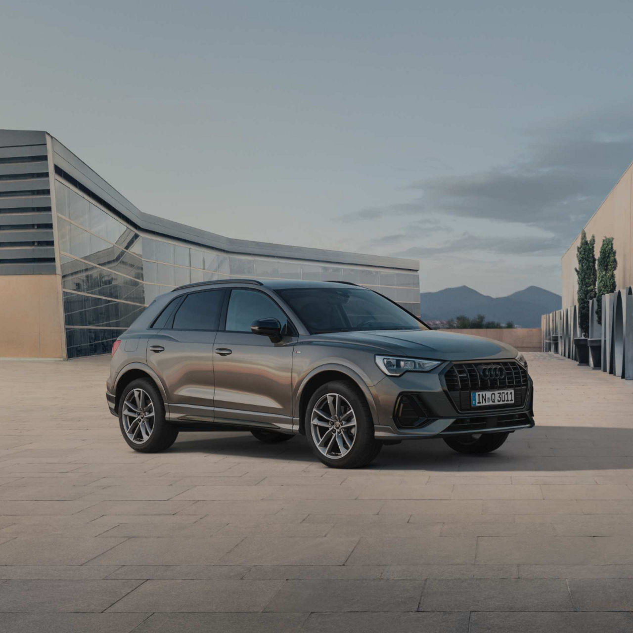 Front angled view of Audi Q3 tfsi e with clear spacious background in front of modern building.