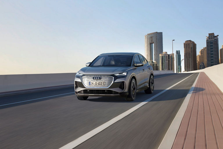 Front view of Audi A4 next to a coastline with a city building skyline background.