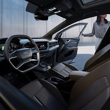 Interior view of front seats with lady entering passenger side of Audi Q4 Sportback e-tron. 