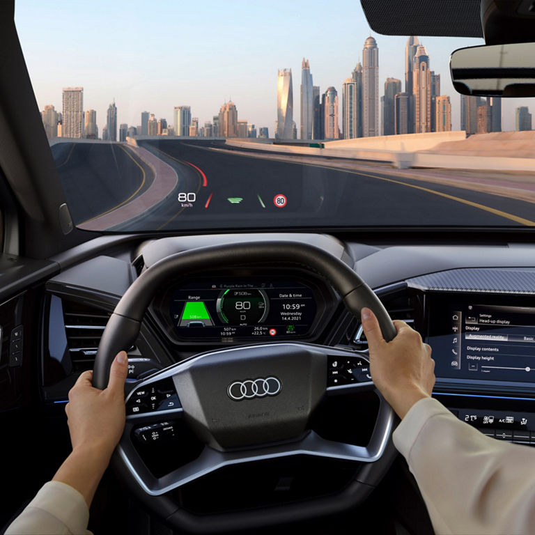 Lady holding steering wheel with both hands and road ahead.