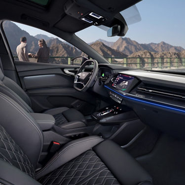 Car interior with leather seats and dashboard, overlooking mountain scenery.