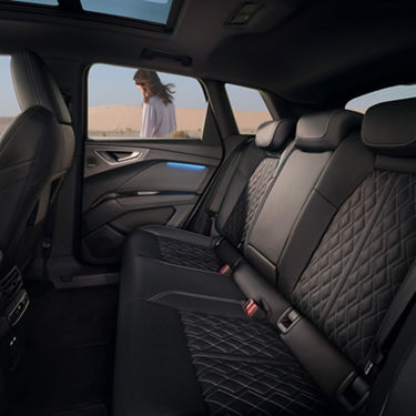 Car interior with quilted leather seats, with a woman visible through the window.