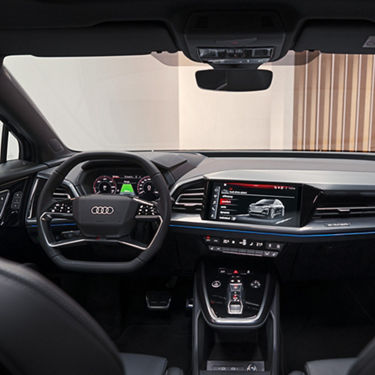 Interior of an Audi car with steering wheel, digital displays, and center console.