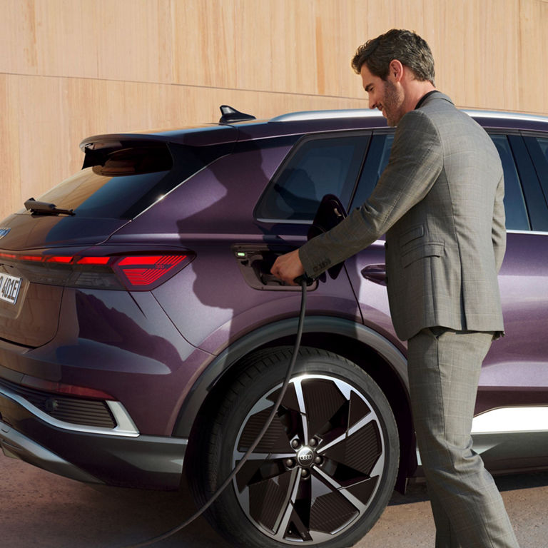 Man at electric charging point charging Audi Q4 e-tron.