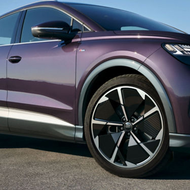 Close-up of a purple Audi's front wheel and door, showcasing its sleek design.