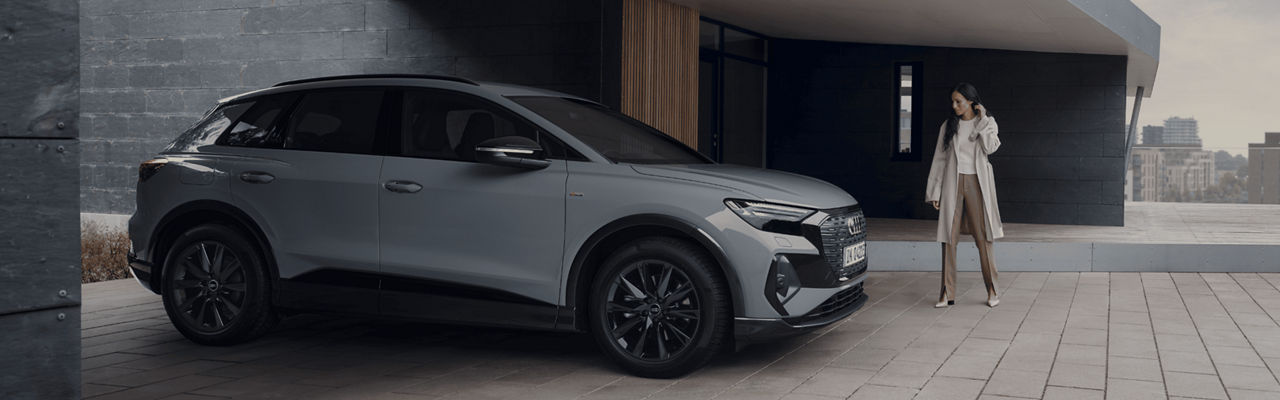 A grey SUV parked outside a contemporary building with a person standing nearby.