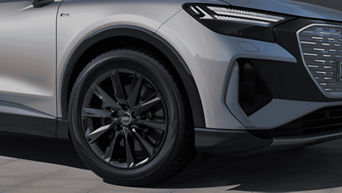 Close-up of a silver Audi's front wheel and partial headlight.