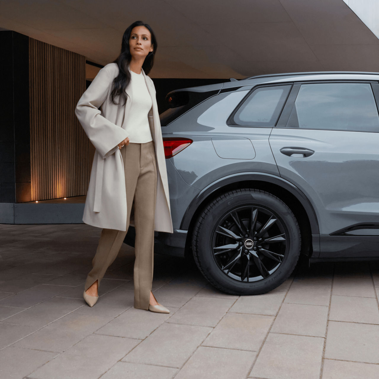  Side view of grey Audi Q4 with lady standing infront of rear end.