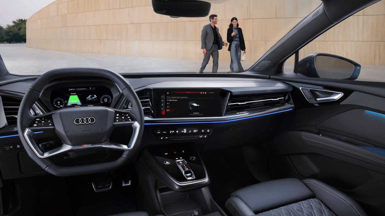 Cockpit view of Audi Q4 e-tron with couple walking on the sidewalk.