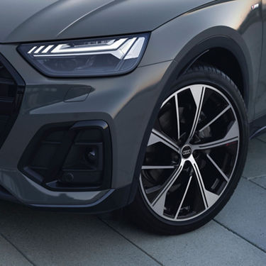 Close-up of a grey Audi's front wheel and LED headlight.