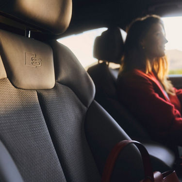 Interior view of a car with a person in the passenger seat and a handbag.