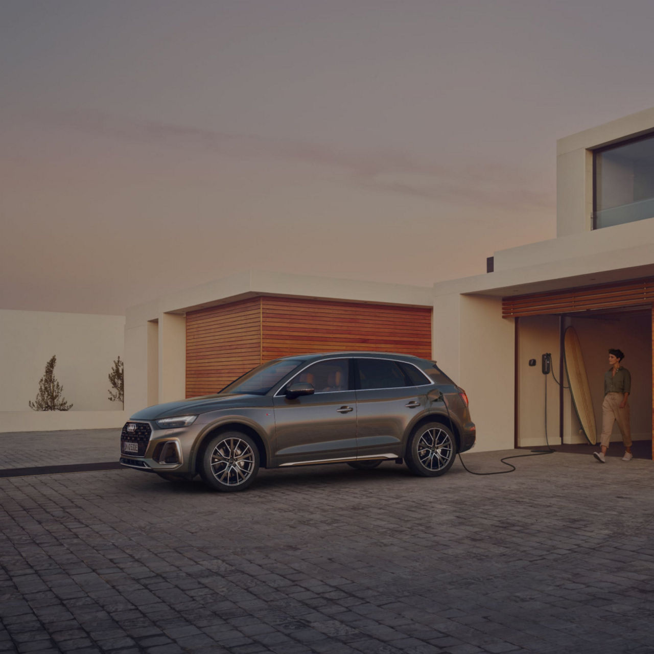 Electric SUV charging outside a modern home at twilight.