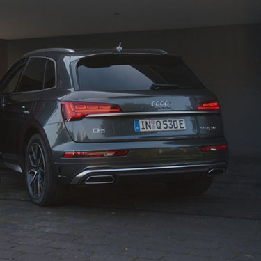 Audi Q5 SUV parked, showcasing its rear design and "Q5 TFSI e" branding.