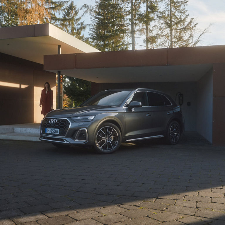 An Audi SUV parked at a charging station outside a modern building.