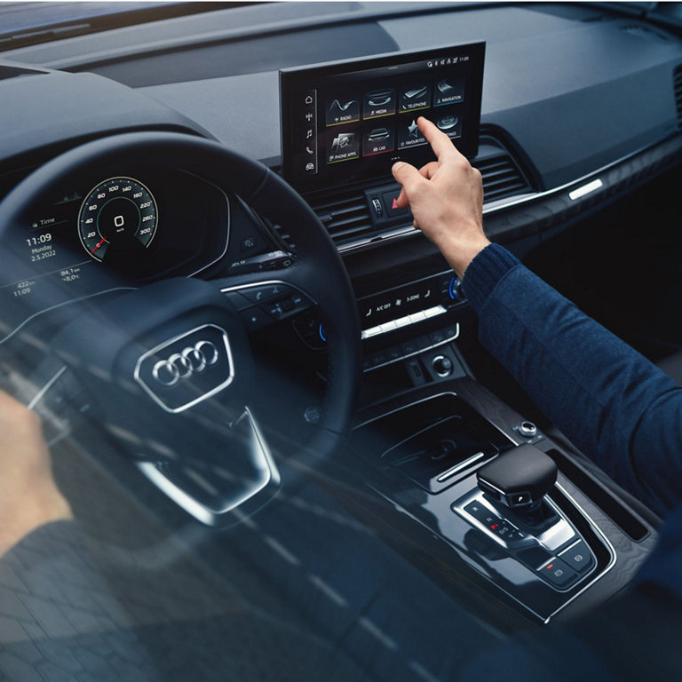 Driver interacting with the touchscreen infotainment system in a car interior.