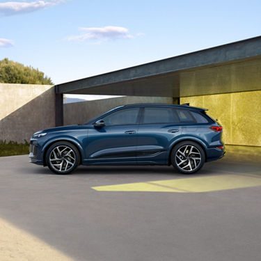 A blue SUV parked near a concrete structure with a golden wall in the background.