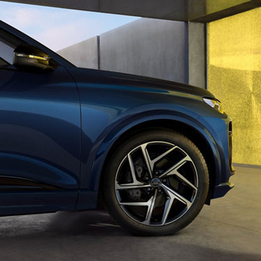 Blue SUV with distinctive headlights and alloy wheels, parked beside a yellow wall.