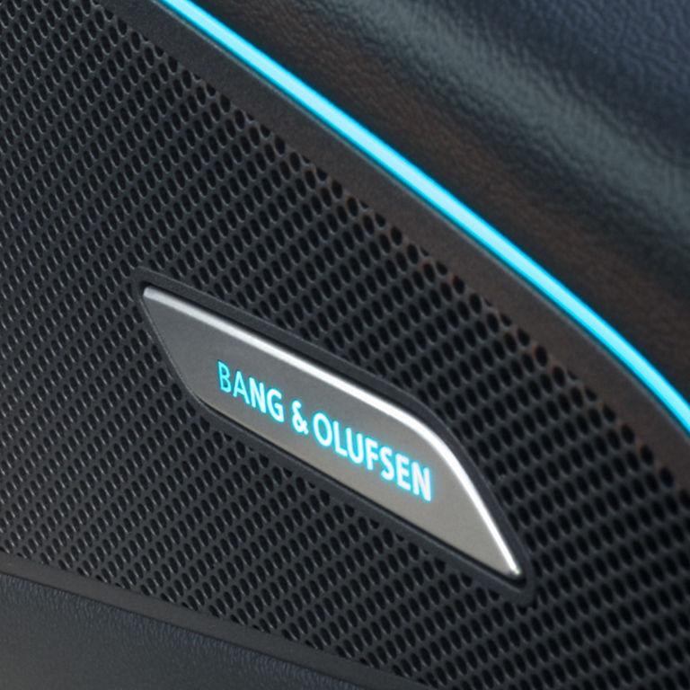 Close-up of a Bang & Olufsen speaker grille with logo and blue accent lighting.