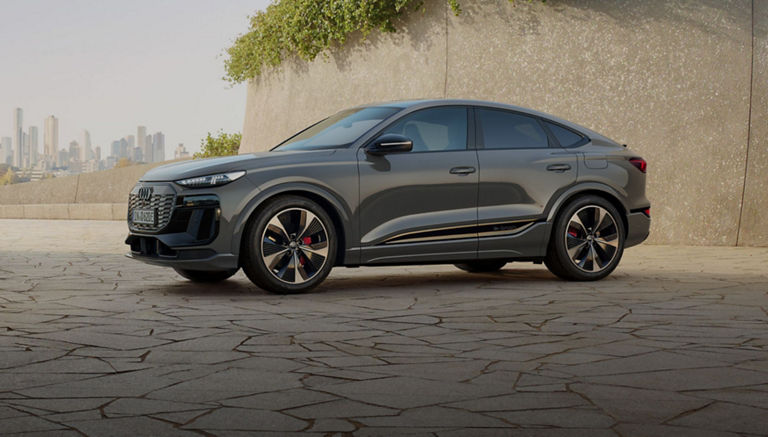 Audi Q6 Sportback e tron parked on a modern designed cracked patio with plants and city skyline in the background.