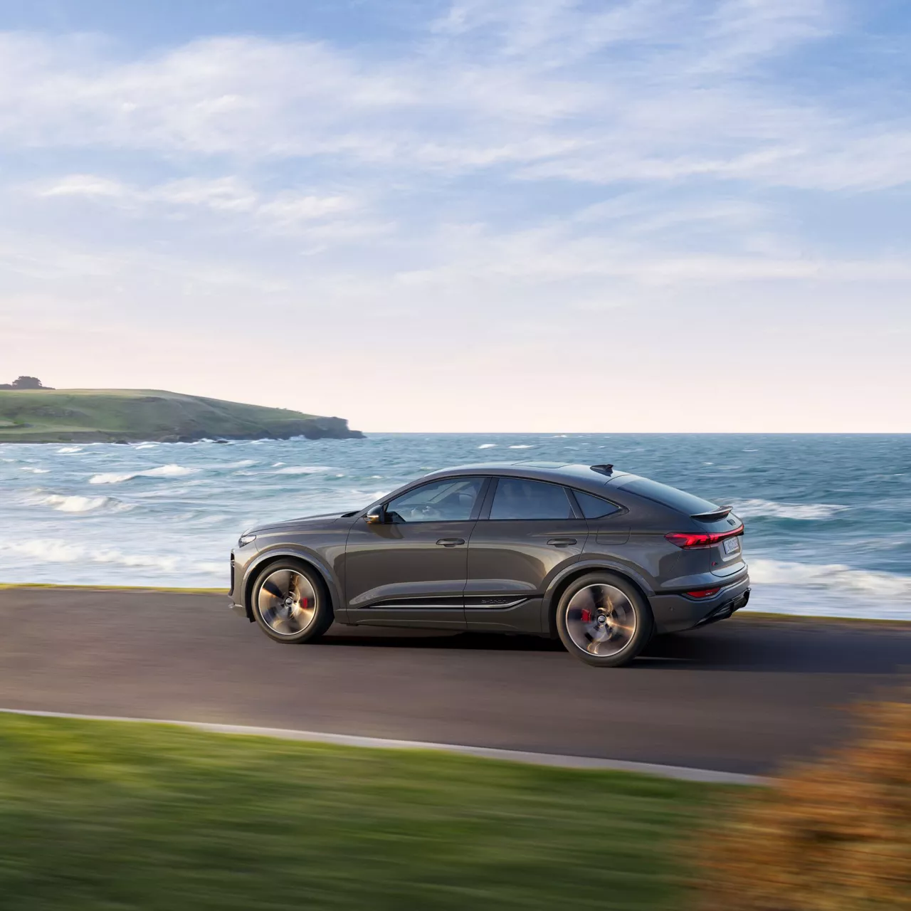 Audi driving along a coastal road.