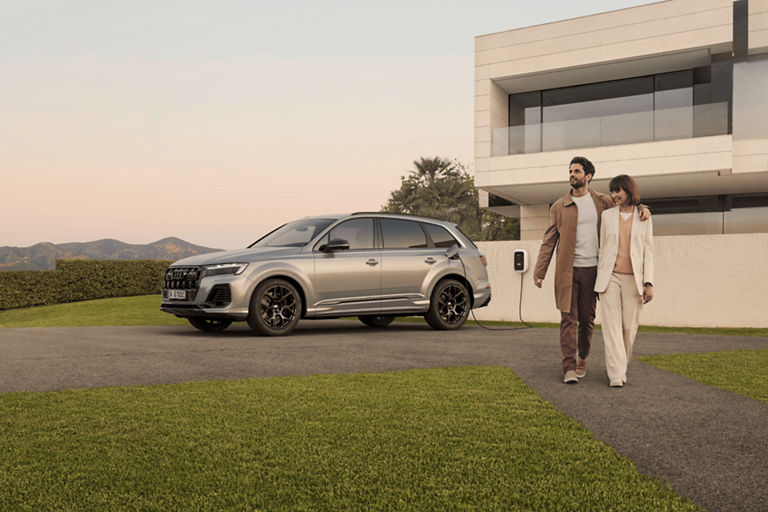 SUV parked outside a modern house with two people walking and holding hands.