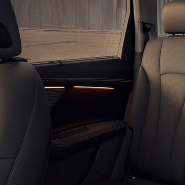 Interior of a car showing a section of the back seat and door with ambient lighting.