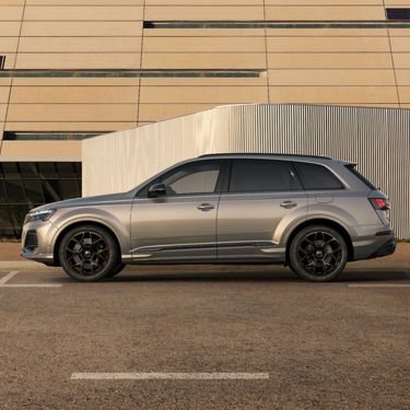 Silver SUV parked outside a modern building at sunset.