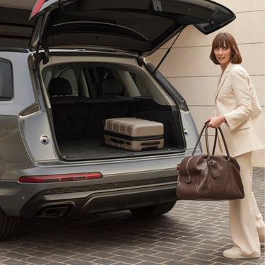 Person loading luggage into the trunk of a SUV.