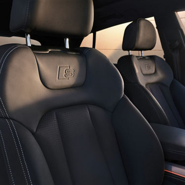 Car interior with leather seats and embroidered logo on headrests.