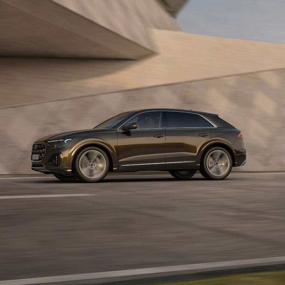 SUV driving past a smooth architectural structure, conveying motion.