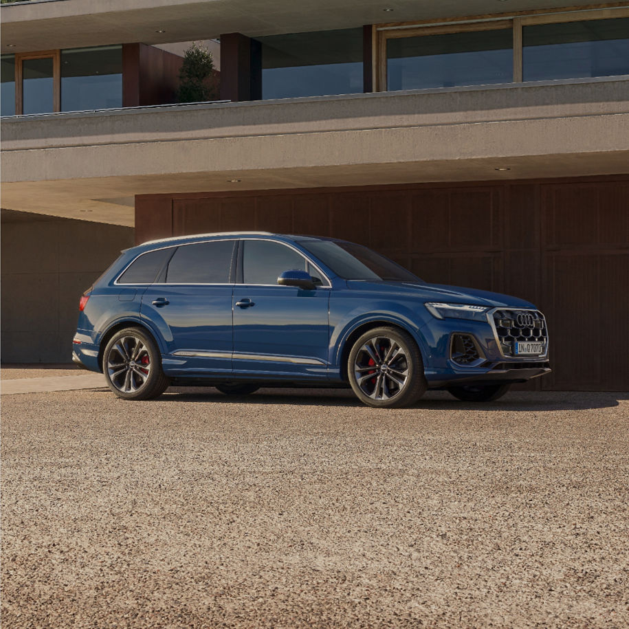 Blue SUV parked outside a modern building with a clear sky overhead.