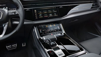 Car interior with leather seats, a dashboard, and dual touchscreens.