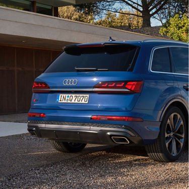 Rear view of a blue Audi SUV with distinctive taillights, parked outside a modern building.