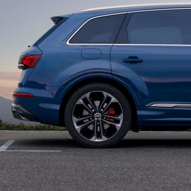  Blue SUV parked outdoors, rear view focusing on wheel and tail lights.